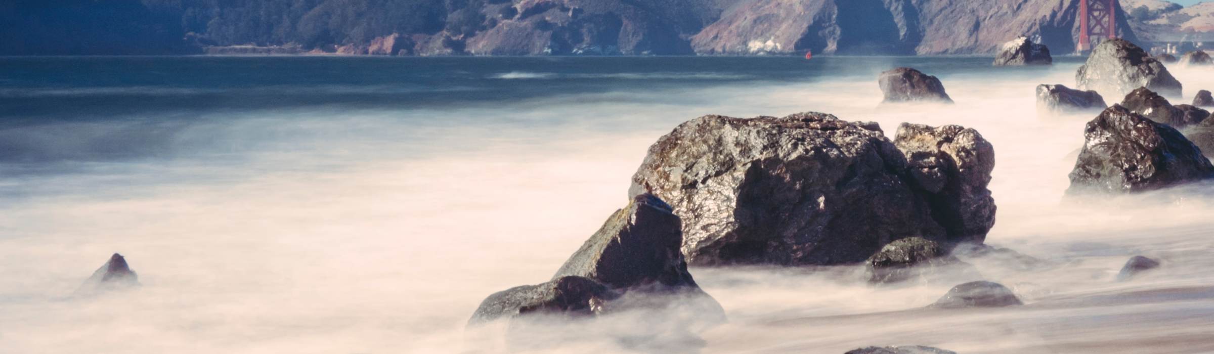 Long-exposure surf washing over rocks on the San Francisco shoreline